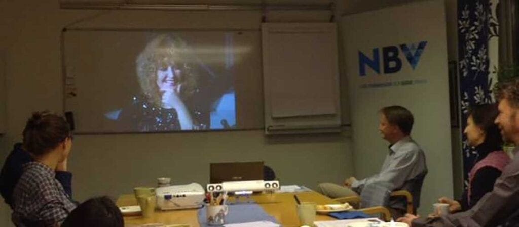 personer som sitter vid bord och tittar på en projicerad bild