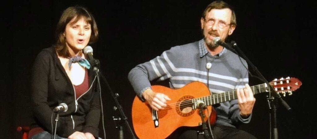 en kvinna som sitter bredvid en man med gitarr