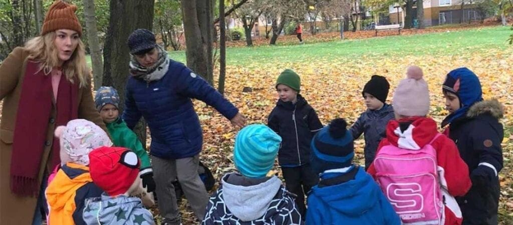 barn och vuxna i en ringlek på gräset under ett träd